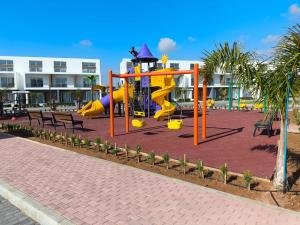 ein Spielplatz mit Rutsche und Bänken vor einem Gebäude in der Unterkunft Luxury Apartment at Four Seasons Life 2 14-B in Vokolidha