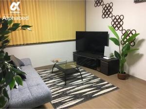 ein Wohnzimmer mit Sofa und Fernseher in der Unterkunft Alphabed Takamatsu Hyogomachi - Vacation STAY 11902 in Takamatsu