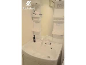 ein Badezimmer mit einem weißen Waschbecken und einem Spiegel in der Unterkunft Alphabed Takamatsu Hyogomachi - Vacation STAY 11902 in Takamatsu