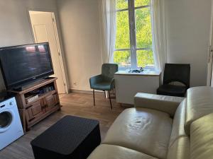 a living room with a couch and a flat screen tv at Chez iris in Noisy-le-Grand
