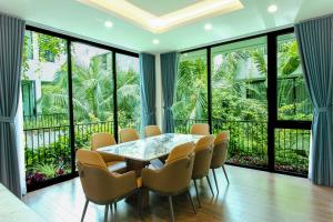 una sala da pranzo con tavolo, sedie e ampie finestre di Charme Villa nighstress flamingo Đải Lải Vĩnh Phúc a Kon Rung (1)
