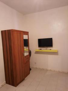 a room with a television and a wooden cabinet at Accueil 1 in Rufisque +6 photos