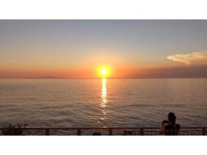 淡路市にあるAWAJISHIMA KOMINKA NO YADO - Vacation STAY 12108の夕日を眺めながらバルコニーに座る女性