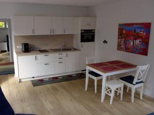 a kitchen with white cabinets and a table and chairs at Ferienwohnung Am Hochrhein in Murg +4 photos