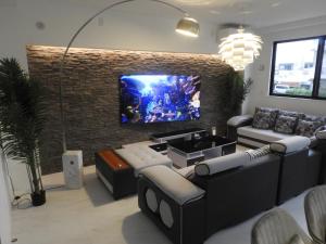 un soggiorno con una grande TV su un muro di mattoni di M's Resort Yomitan Building B - Vacation STAY 80179v a Furugen