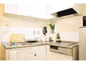 eine Küche mit weißen Schränken, einer Spüle und einer Theke in der Unterkunft OHANA TOKYO HOUSE - Vacation STAY 73216v in Tokio + 10 Fotos