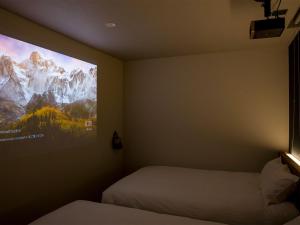 a bedroom with two beds and a large tv on the wall at Rakuten STAY Fuji Kawaguchiko Station - Japanese Modern Villa Mt Fuji View 104 in Fujikawaguchiko