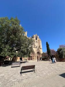 a bench in front of a church with a tree at 3artı1 iki katlı daire in Aglantzia