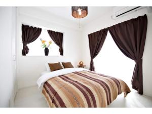a bedroom with a bed with brown curtains and a window at Vent du Vent - Vacation STAY 83347v in Urasoe