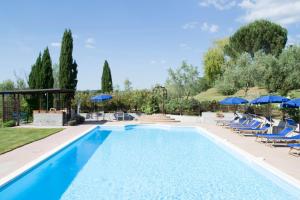 a swimming pool with blue chairs and umbrellas at Agriturismo Cornieto in Monteleone dʼOrvieto