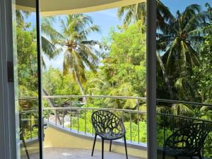 a balcony with two chairs and palm trees at Noah Private Beach House in Himmafushi