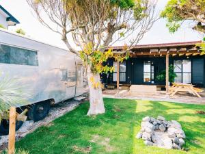 ein Wohnwagen, der vor einem Haus mit einem Baum parkt in der Unterkunft Lagoon Resort - Vacation STAY 96528v in Isumi