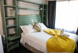 a bedroom with a bed with a yellow blanket on it at Gorgeous Gecko Guesthouse in Modimolle