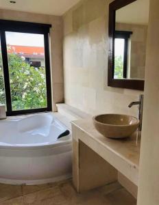 a bathroom with a tub and a sink and a window at Perela Homestay Canggu in Canggu
