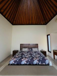a bedroom with a large bed with a wooden roof at Perela Homestay Canggu in Canggu