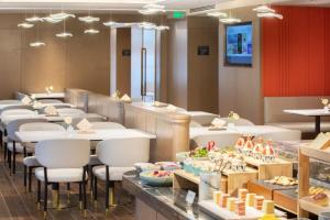 Atour Hotel Xuzhou Chuangtuo Aofan Mining University في سوزهو: مطعم بطاولات بيضاء وكراسي وطعام