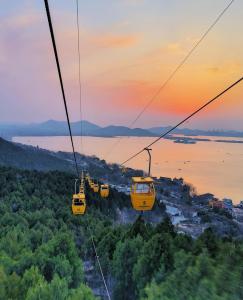 Atour Hotel Xuzhou Chuangtuo Aofan Mining University في سوزهو: مجموعة من عربات الجندول في عربة تلفريك عند غروب الشمس