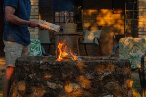 Ein Mann steht neben einer Feuerstelle in der Unterkunft Mackers Self Catering Cottages in Hazyview + 24 Fotos