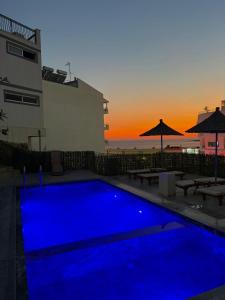 a blue swimming pool with a sunset in the background at Vila Jon'a in Sarandë