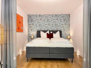 een slaapkamer met een bed met een bakstenen muur bij Kaiser Wilhelm - Altstadt Design Apartment in Freiburg im Breisgau