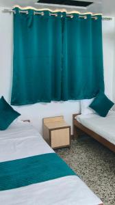 a room with two beds and a blue curtain at Hotel DRS by Vihasta, Balaghat 