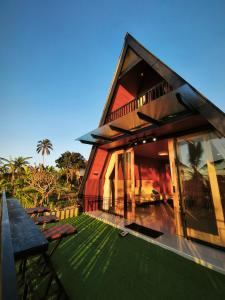 ein Haus mit einem großen Fenster und einem grünen Hof in der Unterkunft Casa Vella Cottage in Patjung