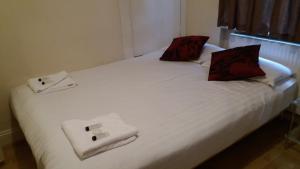 a white bed with red pillows and towels on it at Mayfair Flat in London