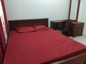 a bedroom with a red bed with a desk and a chair at Nilaro Restaurant in Morawaka