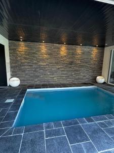 Reventin-VaugrisにあるMaison famillial Des cote d'areyのレンガの壁の客室内のスイミングプール