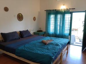 una camera da letto con un letto con lenzuola blu e una finestra di Petit Ana Beach Retreat a Varkala Altre 23 foto