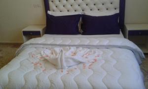 a bed with white sheets and flowers on it at Hotel School Ersat Azrou in Azrou