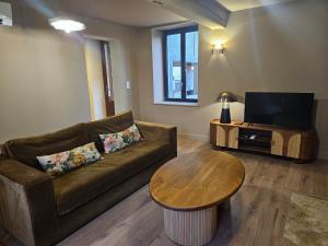 a living room with a couch and a table and a tv at La Maison des Chouettes in Maisons-lès-Chaource