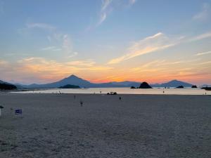a sunset on a beach with mountains in the background at Minshuku Kakutani Hitohira - Vacation STAY 16023v in Wada