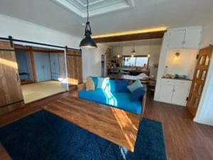 a living room with a blue couch and a kitchen at Poroto Base - Vacation STAY 18129v in Shiraoi +6 photos
