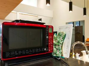 a red microwave sitting on a kitchen counter next to a sink at Forest Villa Nanso no Oka - Vacation STAY 39402v in Minamiboso +28 photos