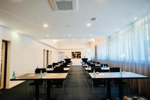 a room with tables and chairs in a room with windows at Arthotel Ambassador Wiesbaden - FREE PARKING in Wiesbaden