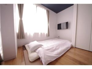 a bedroom with a white bed and a large window at HOTEL APT SESELA - Vacation STAY 12884 in Kanazawa