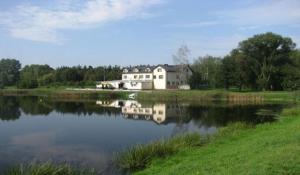 dom odbija się w wodzie jeziora w obiekcie Hotel Czardasz we Wrześni