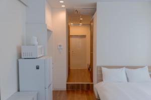 ein Schlafzimmer mit einem weißen Bett und einer Mikrowelle in der Unterkunft RIVER VILLAS HIROSHIMA - Vacation STAY 24194v in Hiroshima