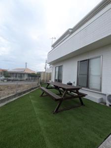 a wooden picnic table sitting on a lawn next to a building at NAGI - Vacation STAY 41896v in Nanjo