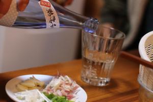 une personne verse de l'eau dans une assiette de nourriture dans l'établissement Minamitsuru-gun - Cottage - Vacation STAY 59712v, à Yamanakako