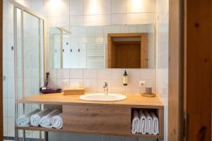 une salle de bain avec un lavabo et un miroir dans l'établissement Dorfchalets - Chalet Dora inkl Tauern Spa Eintritt & Sommerkarte, à Kaprun 9 autres photos