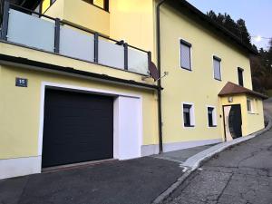 a yellow and white building with a garage at Klein aber fein in Spittal an der Drau