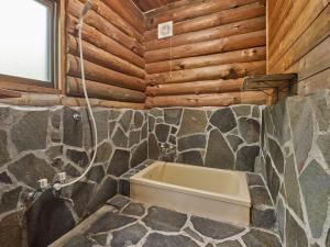 ein Badezimmer mit einer Badewanne in einer Holzwand in der Unterkunft Runesu Karuizawa - Vacation STAY 92241v in Tsumagoi + 13 Fotos