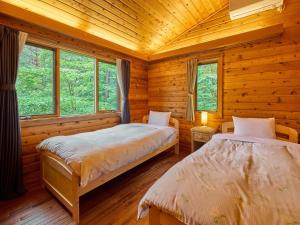 two beds in a log cabin with windows at Runesu Karuizawa - Vacation STAY 92236v in Tsumagoi