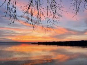 a sunset over a large body of water at Helle Gartenwohnung, 2 min zum See, in Herrsching in Herrsching am Ammersee +12 photos