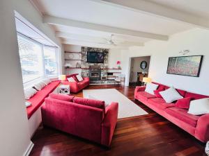 a living room with red couches and a fireplace at Luxury 5-Bedroom Ocean-View Coastal Escape in Busselton