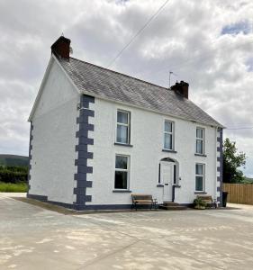 a white house with a bench in front of it at Castleroddy House in Lislap