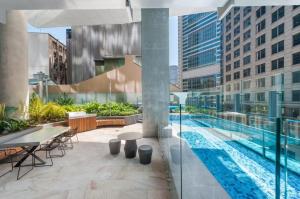 an outdoor patio with a pool and tables and chairs at Sydney CBD Top level 2 bedroom Condo with amazing view Pool Gym 3 in Sydney