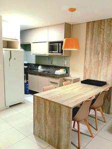 una cucina con tavolo con sedie e frigorifero di Flat Beira Mar - Carneiros Beach Resort a Tamandaré